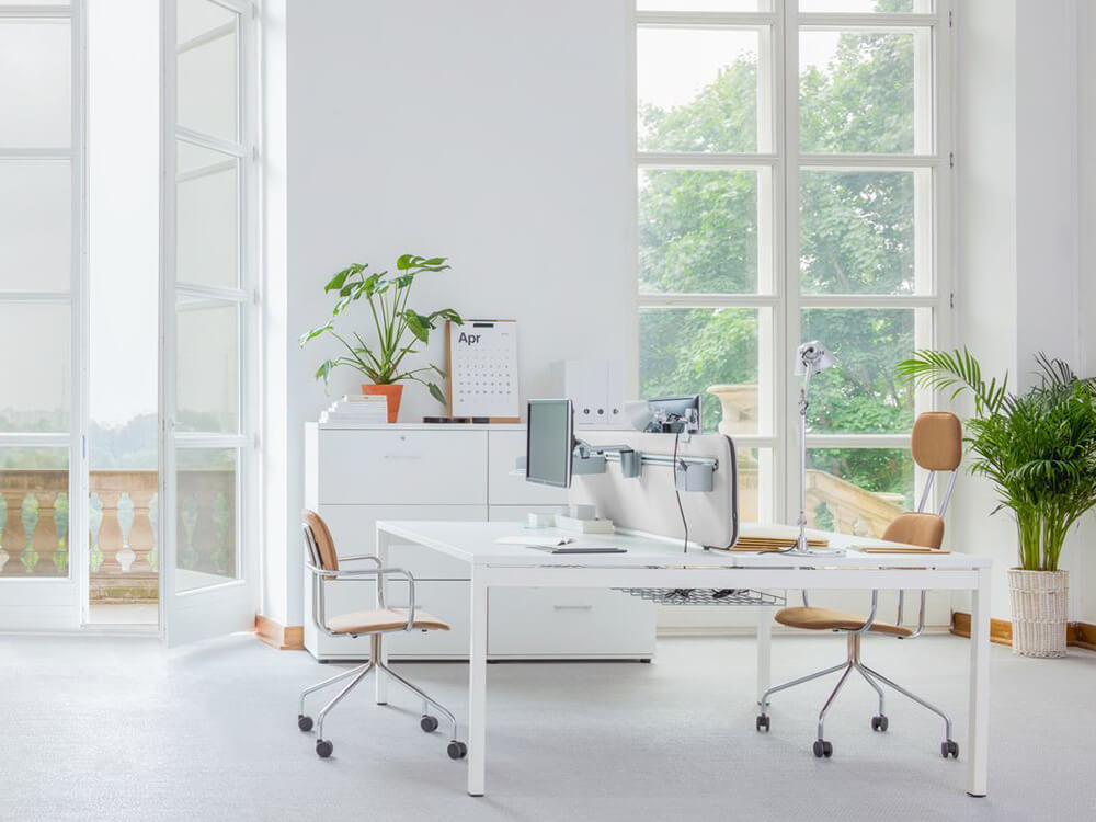 A workspace with light-coloured modern office furniture near the window to receive maximum sunlight.