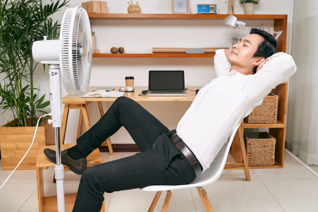 A businessman relaxing in a well-lit office, surrounded by modern office furniture and an advanced HVAC system.