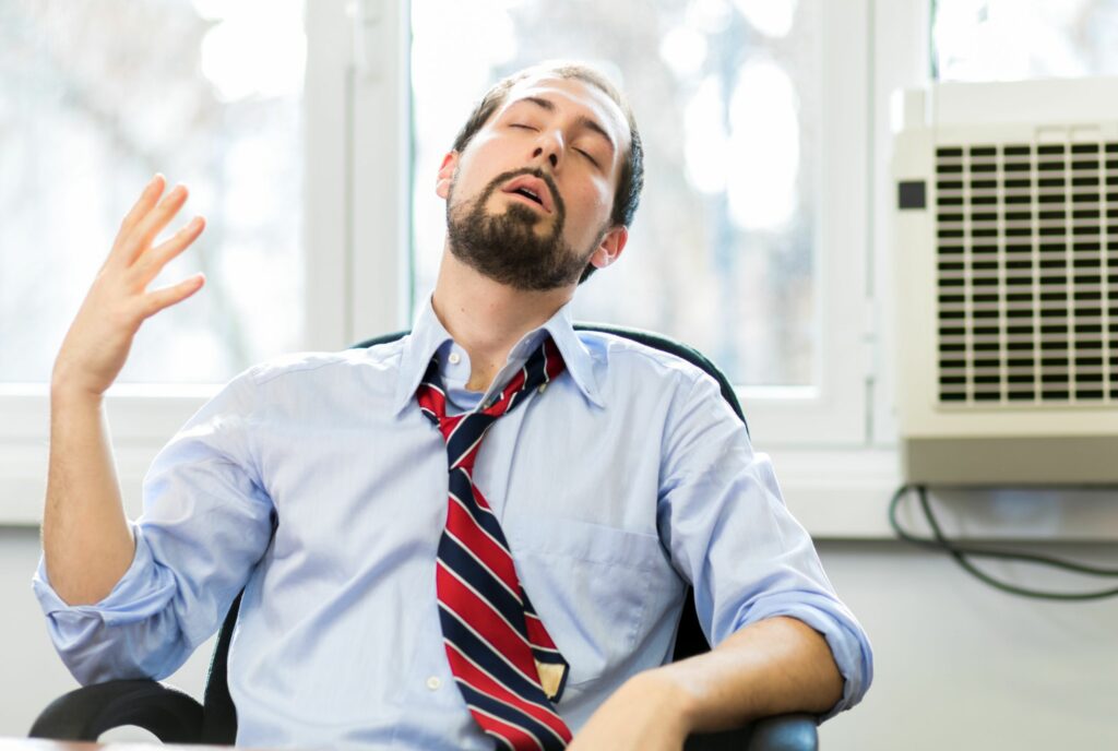 A finance advisor sweating and loosening his tie, highlighting the importance of temperature regulation in creating a comfortable environment for clients in finance firms.