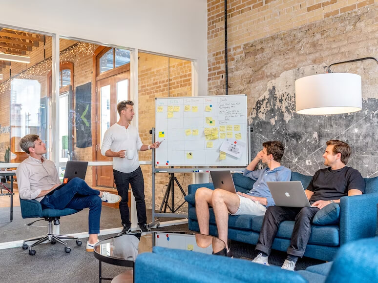 A group of professionals indulged in a brainstorming session using a reusable whiteboard to jot down ideas and concepts.
